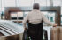 Rear view of man on wheelchair at airport with his luggage.