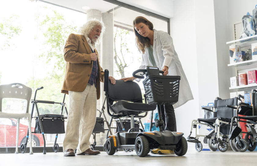 Staff showing electric scooter to senior man